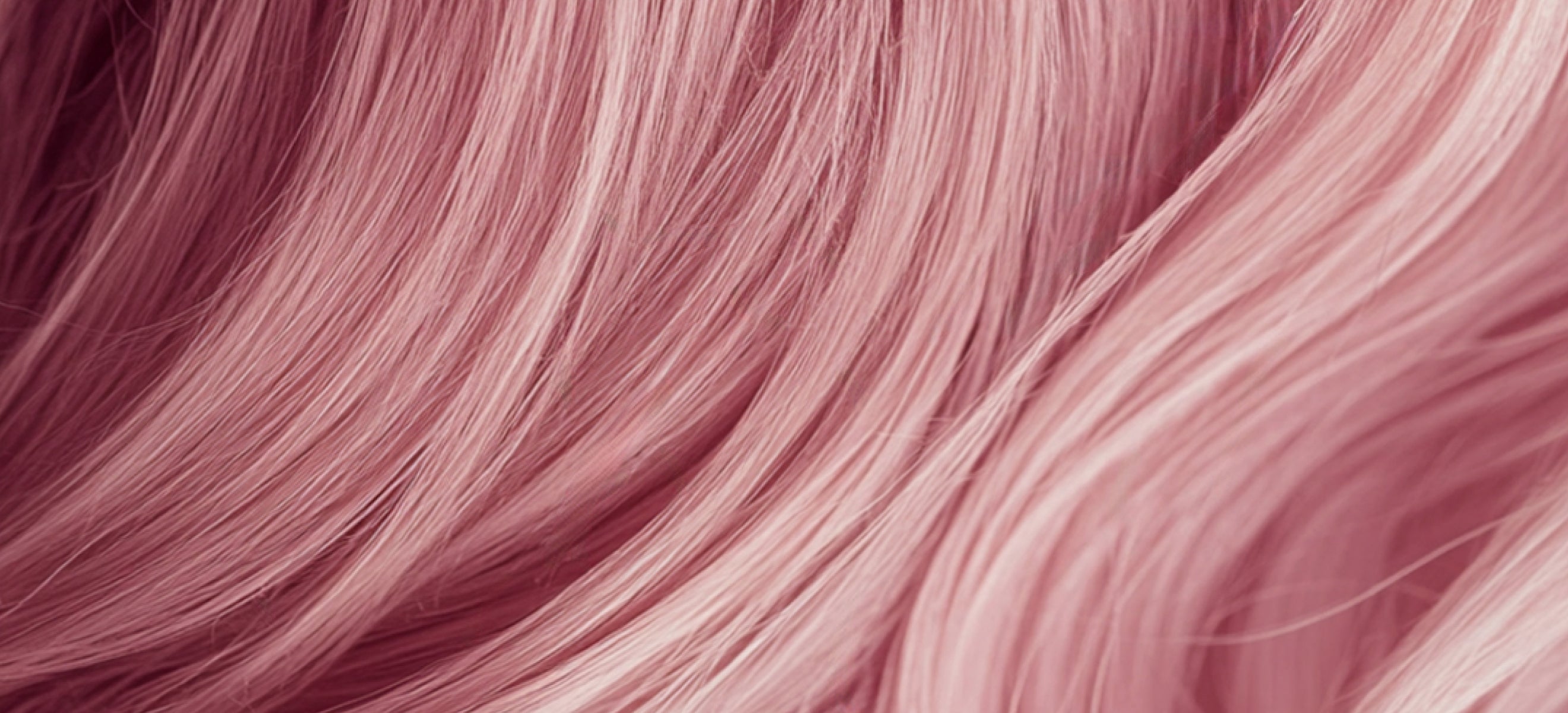 A close-up view of a woman's hair showcasing vibrant pink extensions.